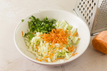 Preparation of cabbage salad. Vegetables are rubbed into a white bowl. Tasty and healthy food.