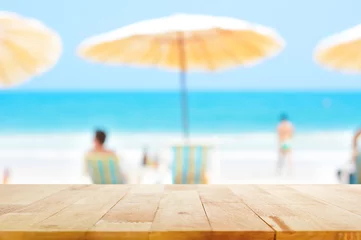  Wood table top on blurred blue sea and white sand beach background with some people © Atstock Productions