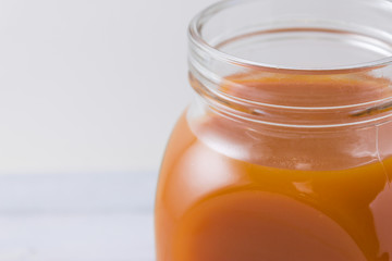 Carrot and apple grape juice in glass jars on a wooden table