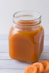 Carrot and apple grape juice in glass jars on a wooden table