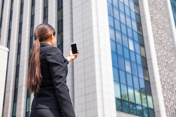 young businesswoman taking a picture of building