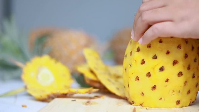 Close up shot hands of women using kitchen knife to cutting and peeling ripe pineapple shallow depth of field with ambient sound 