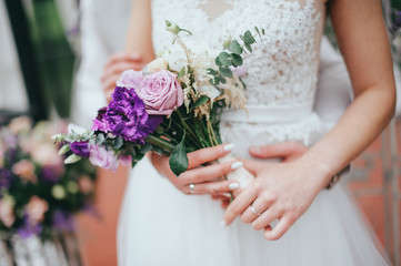 Obraz na płótnie Canvas Stylish beautiful bride holds a wedding bouquet in hands