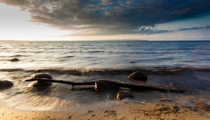 Blick auf Meer mit Wellen, Felsen, Himmel und Wolken bei Sonnenuntergang