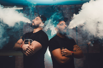Two men vaping in an authentic room with brick walls