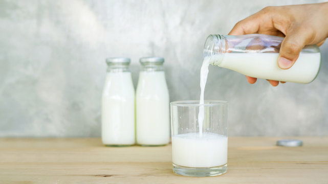 man pouring a milk on a wooden table.