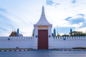 Big wooden gate with caption "Sawasdeeloke" of the Emerald Buddha or Wat Phra Kaew Temple at evening or sunset time in Bangkok, Thailand.