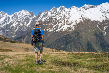 Fototapeta premium Man hiker goes along alpine meadow