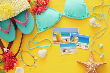 Top view of fashion female swimsuit bikini on yellow wooden background. Summer beach vacation concept