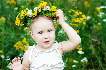 Portrait of a little girl in a wreath from wild flowers. Child closeup.