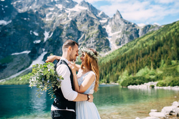bride with the beautiful blue dress and groom hugging with views of the beautiful green mountains...