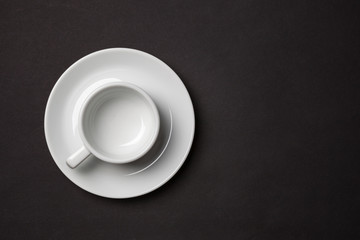 Empty white cup for espresso with saucer on black background.