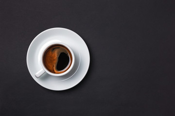 Cup of espresso with sauser on black background.