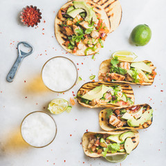 Healthy corn tortillas with grilled chicken, avocado, fresh salsa, limes, beer in glasses over light grey marble background, top view. Healthy food, gluten-free, allergy-friendly concept. Square crop
