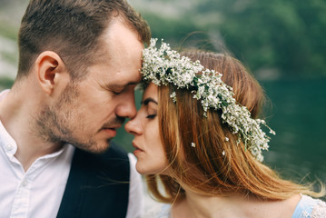 bride with a beautiful wreath of white flowers and the groom standing face to face