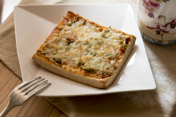 Pizza toast with cheese and fork on the white plate.