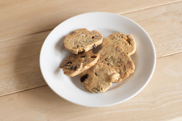 Nuts cookies in small white bowl isolated on wooden background.