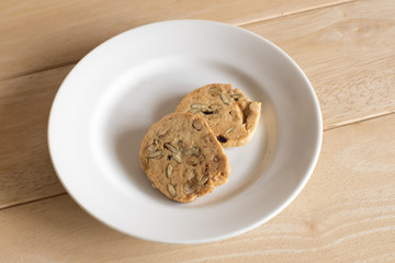 Nuts cookies in small white bowl isolated on wooden background.