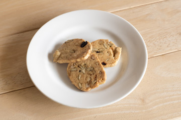 Nuts cookies in small white bowl isolated on wooden background.