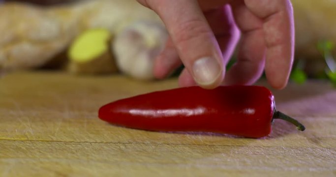 Red Chilli falls onto wooden chopping block