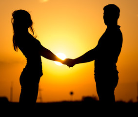 Silhouette of a guy and a girl at sunset