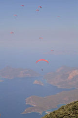 Paraglider flies in the sky. Panoramic bird's-eye view on Turkey, Oludeniz, Mediterranean. Paragliding is a free flying sport where the pilot launches themselves by foot.