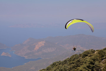 Paraglider flies in the sky. Panoramic bird's-eye view on Turkey, Oludeniz, Mediterranean. Paragliding is a free flying sport where the pilot launches themselves by foot.
