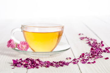 Rose tea and dried petals on white wooden table
