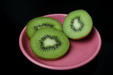 Fresh kiwi fruits in pink dish on wooden floor and brick background.Ripe kiwi fruits.