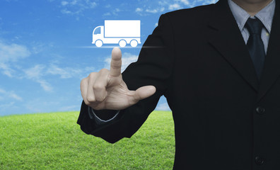 Businessman pressing truck flat icon over green grass field with blue sky, Business transportation service concept