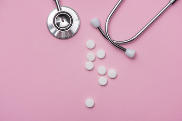 Medical concept. Stethoscope and pills on pink background.