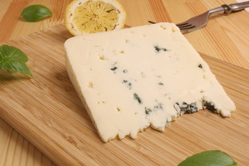 blue Cheese on a wooden board with basil