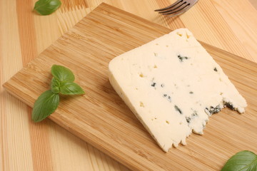 blue Cheese on a wooden board with basil