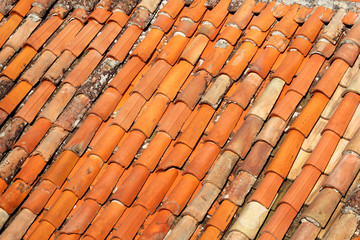 Part of tile on the roof of a house building, closeup. A red tiled terracotta roof. The orange roof tiles, maps and textures. Texture of tiles. Background with part of roof. Rows of roof bricks.