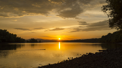 Obraz premium summer sunset on beach by river. cloudy beauty sunset in summer
