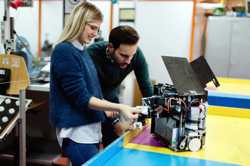 Young students of robotics preparing robot for testing