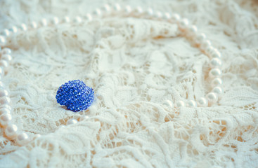 Vintage tenderness wedding accessories. Stylish colorful blue jewelry with stones on a white lace. 