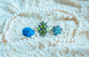 Vintage tenderness wedding accessories. Stylish colorful jewelry with stones on a white lace. 