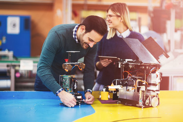 Young students of robotics preparing robot for testing