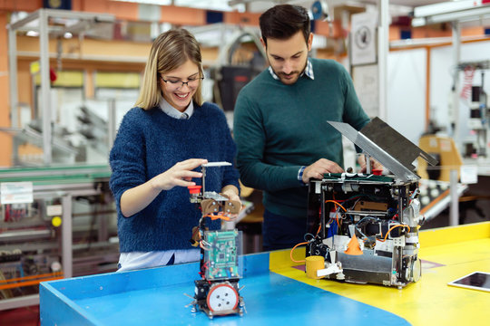 Young students of robotics preparing robot for testing