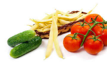 Fresh young pods of beans with beans, bunch of the fresh red tomatoes and several green cucumber with water drops on white background..