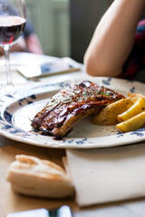 Delicious grilled pork ribs with barbecue sauce, over old ceramic plate, in the restaurant