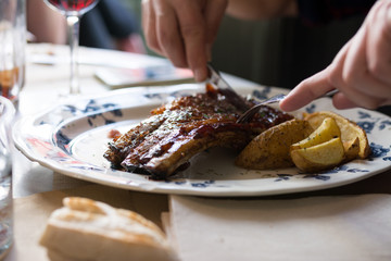 Obraz na płótnie Canvas Man cutting pork ribs on the barbecue in restaurant, close up