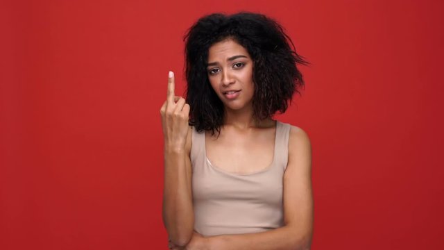 Young angry african woman showing middle finger over red background