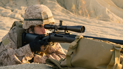 Close-up Shot of Sniper Lying Down on the Hill, Aiming through the Rifle Scope in Desert Environment