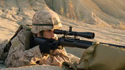 Close-up Shot of Sniper Lying Down on the Hill, Aiming through the Rifle Scope in Desert Environment