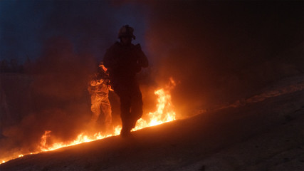 Group of Armed Soldiers Running through Fire During Night Military Operation.