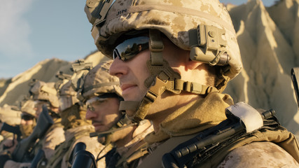 Close-up Shot Group of Fully Equipped Soldiers Standing in a Line in the Desert.