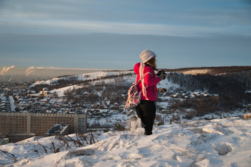 Girl tourist in a red jacket photographs the winter landscape on the camera. The tourist takes off...