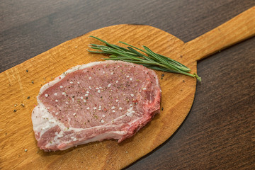 Raw pork steak with salt pepper ans rosemary on wooden board